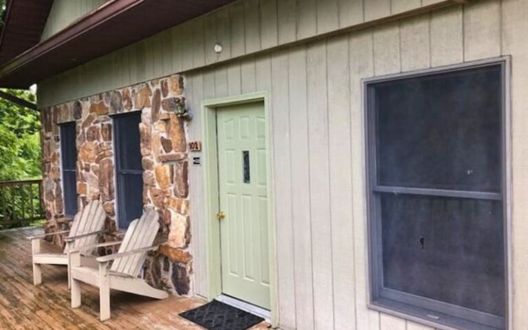 Rustic cabin exterior with green door, Adirondack chairs