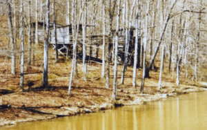 Wooden structures in a winter forest by a river.