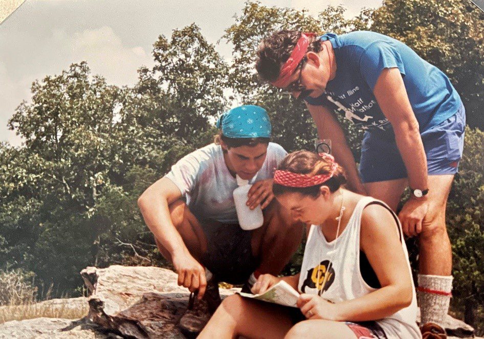 Three people studying a map outdoors.