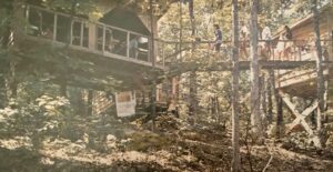 Wooden treehouse with people on a balcony.