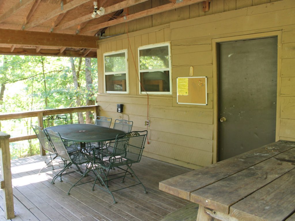 Wooden cabin porch with table and chairs.