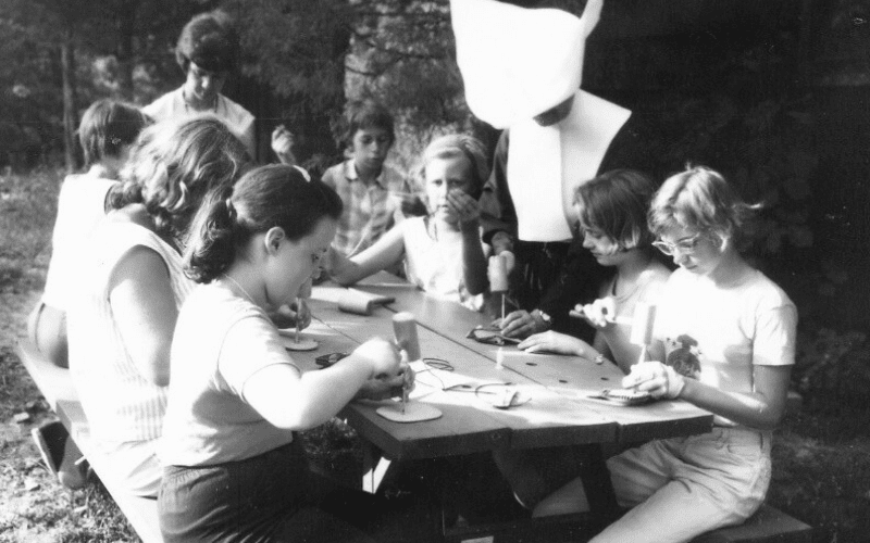 Girls crafting with a nun outdoors.