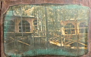 Vintage photo of two cabins in woods.