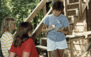 Woman teaching girls crafts outdoors.
