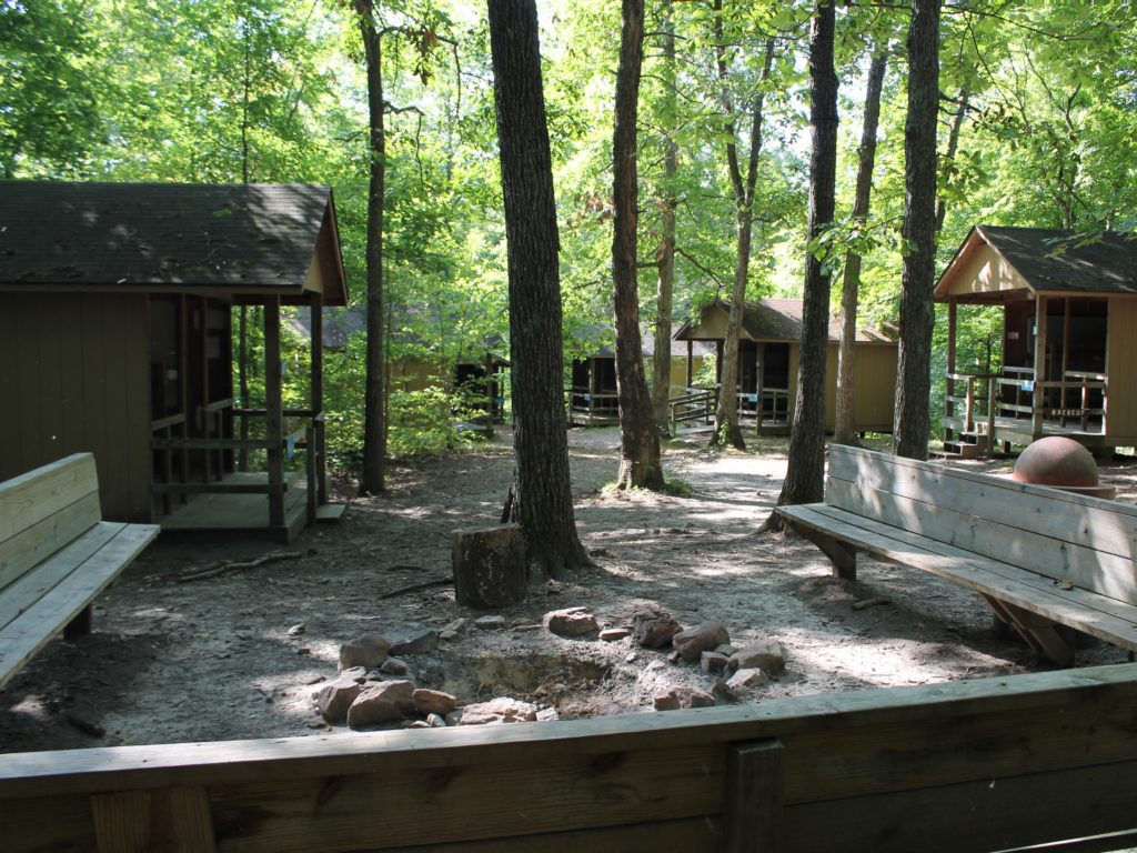 Wooded camp cabins with benches around fire pit