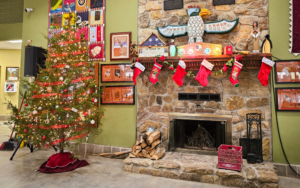 Christmas tree by stone fireplace with stockings.
