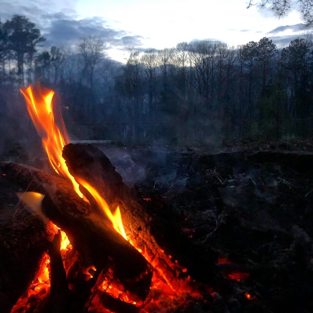 A Father-Son weekend campfire in the woods at dusk.