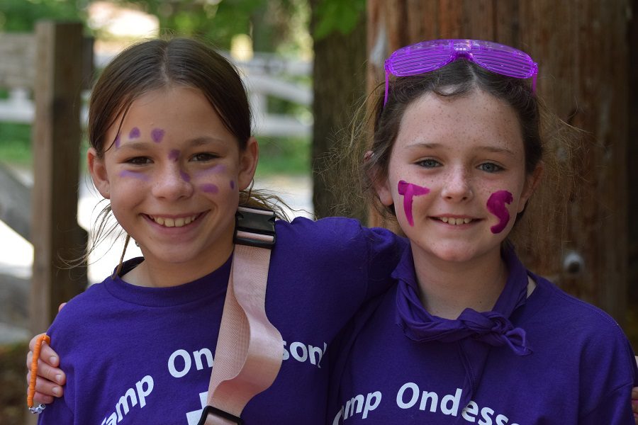 Two girls in purple shirts smiling.