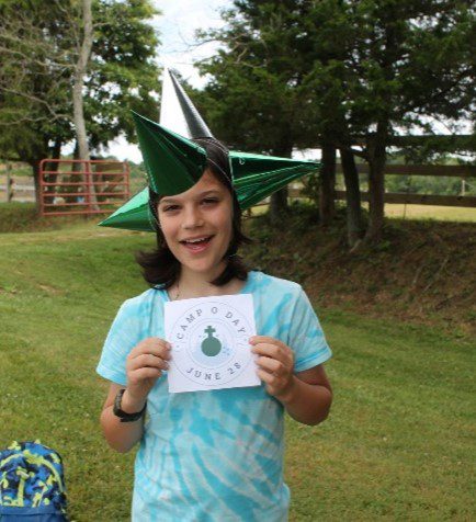 Girl wearing a star hat and holding a camp sign.