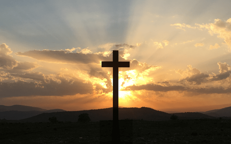 Sunset cross silhouette, peaceful landscape.