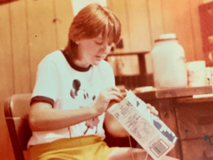 Young girl in Mickey Mouse shirt holding box.