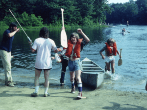 Group of people at a lake with a canoe.