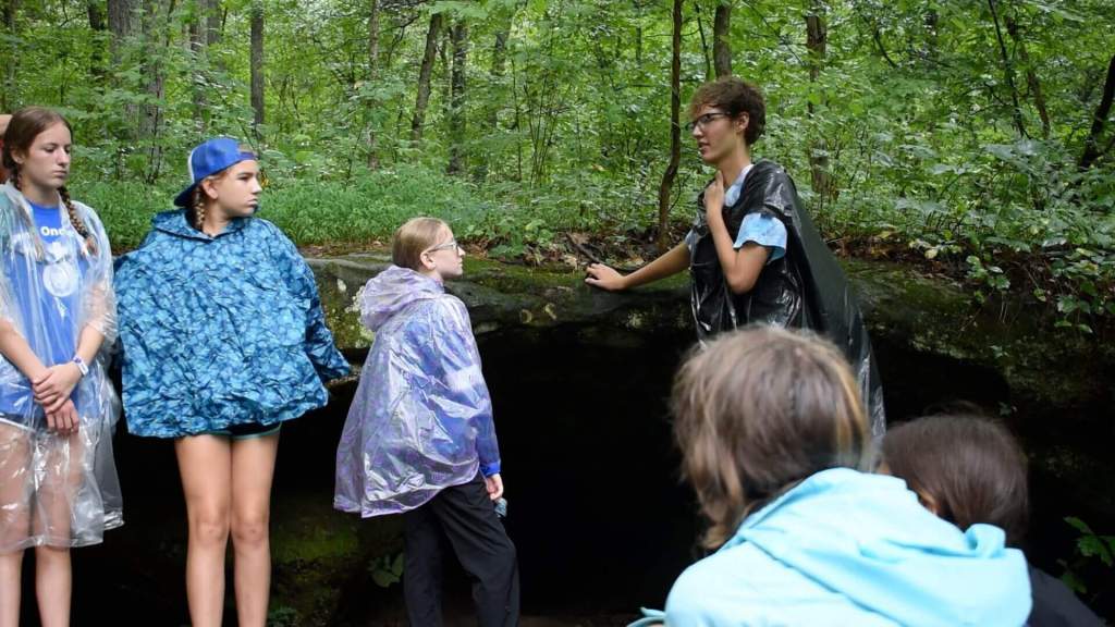 Group of kids in ponchos near forest cave