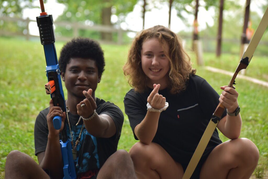 Two people holding a toy gun and bow