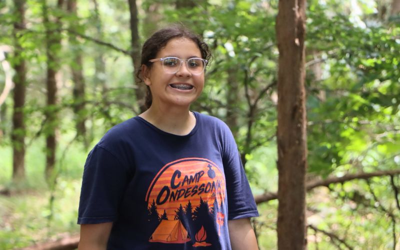 Smiling teen in camp t-shirt in forest