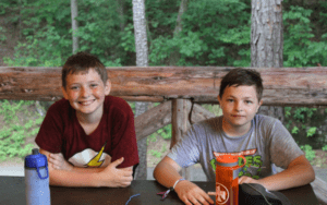 Two boys smiling outdoors at camp.