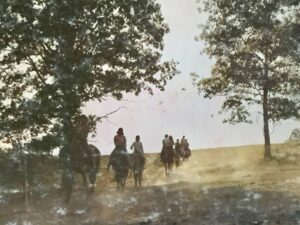People horseback riding through a field.