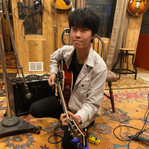 Teenager playing guitar in recording studio.