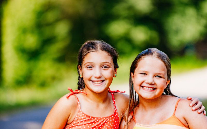 Two girls smiling outdoors in summer dresses.