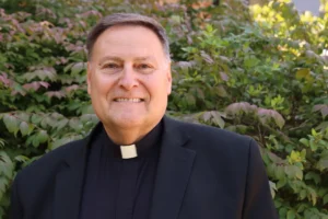 Smiling man in a clergy collar.