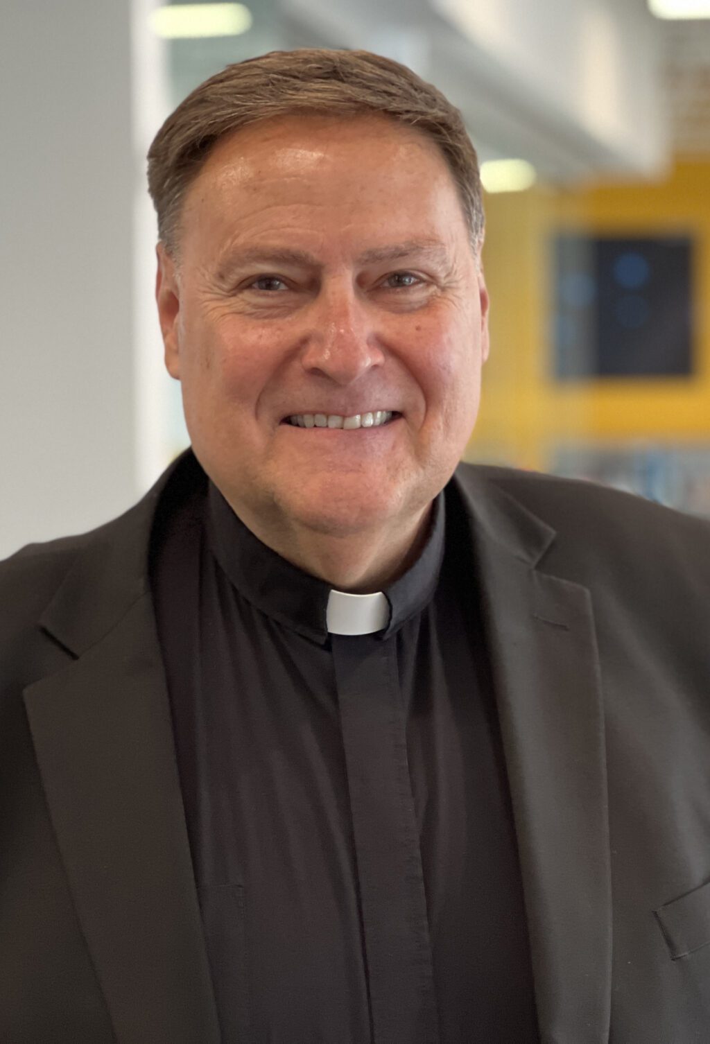Smiling man wearing a clergy collar.