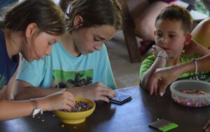 Three children making crafts with beads.