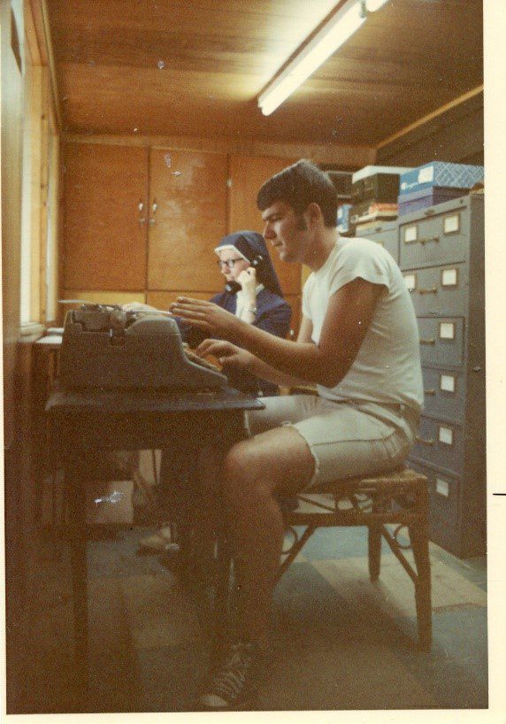 Man typing on a typewriter with a nun.