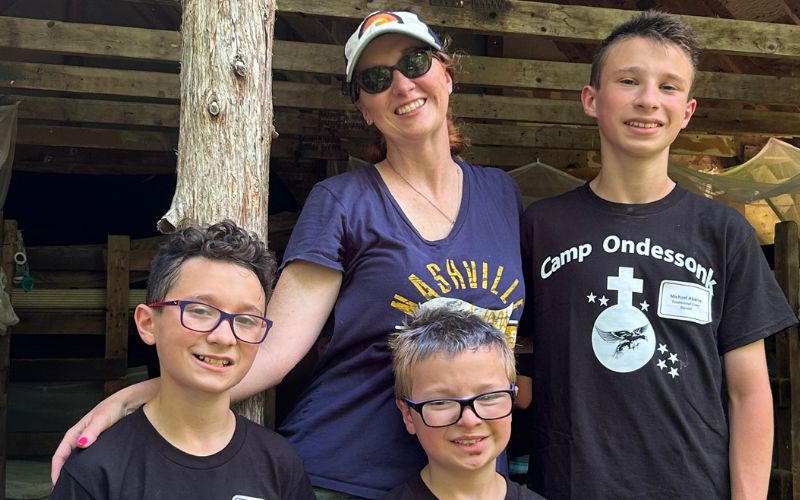 Smiling woman with three boys at summer camp