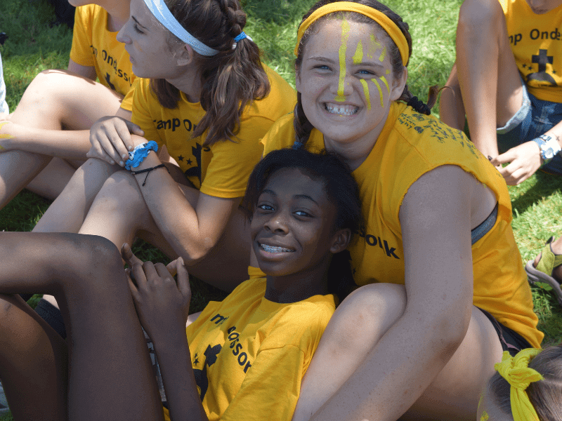 Four girls wearing yellow camp shirts.