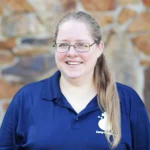 Woman wearing blue camp shirt and glasses.