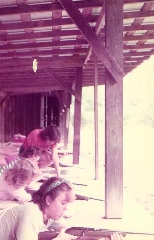 Girls shooting rifles under a porch