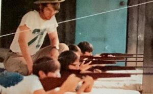 Man teaching young people rifle shooting.