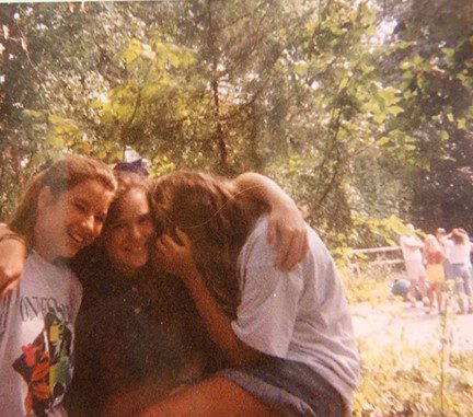 Three girls hugging in the woods.