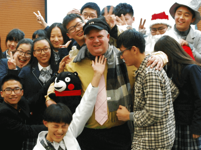 Group of students around smiling man with plush