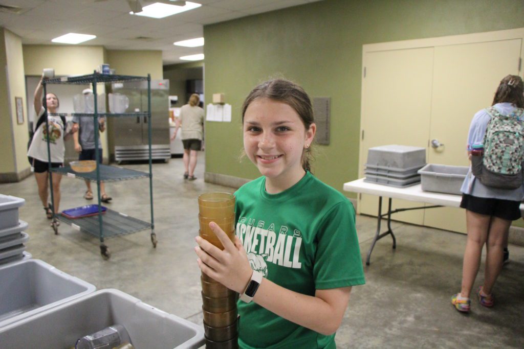 Smiling girl holding stacked cups in kitchen
