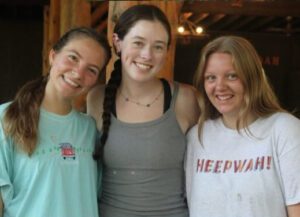 Three smiling friends standing together indoors