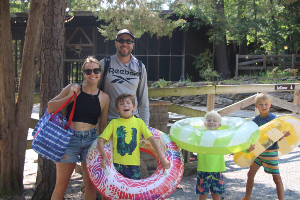 Family posing with pool floaties outdoors.