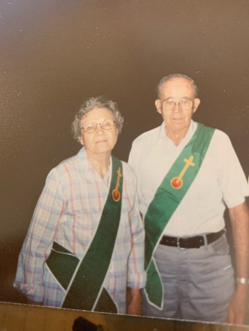 Elderly couple wearing green sashes with crosses.