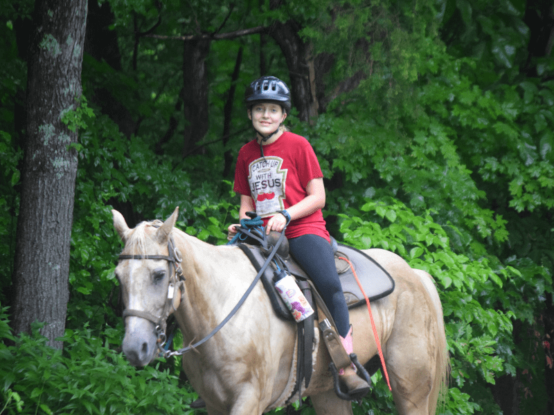 Young rider on palomino horse in forest