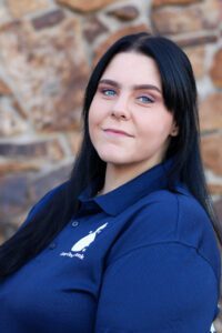 Woman in blue shirt with logo smiling.