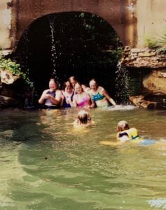 Girls swimming under a waterfall.