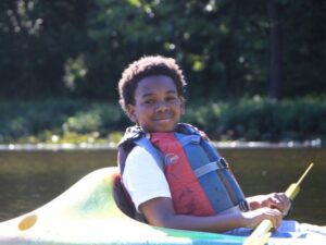 2024 Campers Benefit from the Scholarship Fund. Camper floating in a kayak.