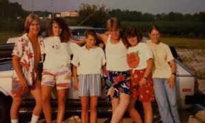Group of friends posing by a car.
