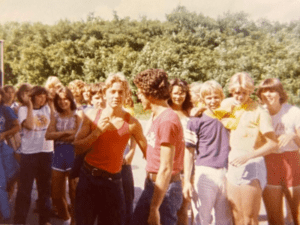 Group of teens in 70s attire outdoors.