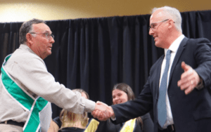 Two men shaking hands at ceremony.