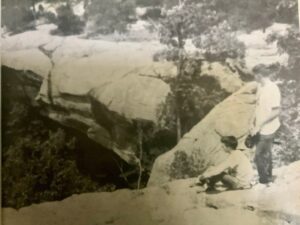 Two people sitting on a rock in a forest.