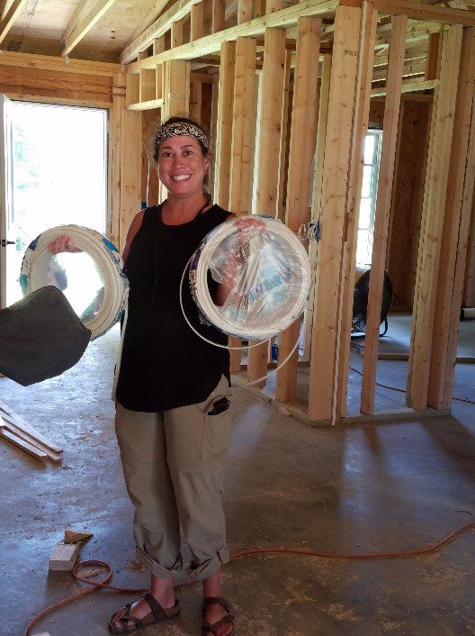 Woman holding coils of wire in unfinished room.