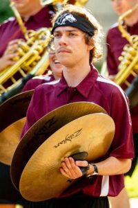 A young man playing cymbals in a band.
