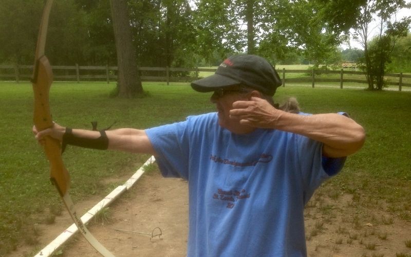 Archer pulling bowstring in grassy park