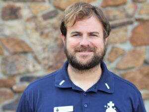 Smiling man wearing blue polo shirt.